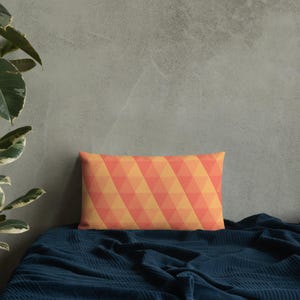 May include: A rectangular cushion with a geometric pattern of orange and yellow triangles. The cushion is on a blue blanket.