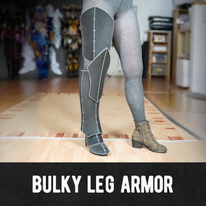 Könnte beinhalten: Schwarze und graue, klobige Beinschutzpanzerung mit weißen Nähten wird an einem Bein gezeigt. Die Panzerung besteht aus einem starren Material und dient zum Schutz des Beins. Der Text "BULKY LEG ARMOR" wird am unteren Bildrand angezeigt.