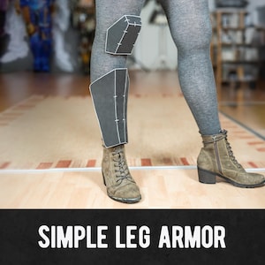 Può includere: Una persona indossa leggings grigi e stivali scamosciati marroni con una semplice armatura per le gambe attaccata. L'armatura è nera con cuciture bianche ed è attaccata alle ginocchia e alla parte inferiore della gamba. Il testo "SIMPLE LEG ARMOR" è in basso nell'immagine.
