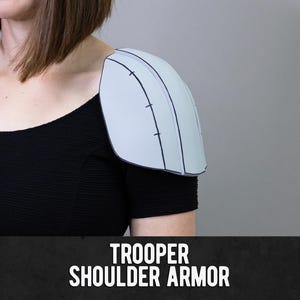 May include: A light blue shoulder armour piece with black outline details is worn on a person's shoulder. The armour is a light blue colour. The text "TROOPER SHOULDER ARMOR" is displayed in white letters on a black background.