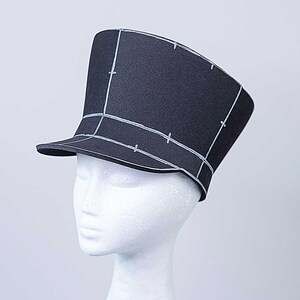 May include: A black foam hat with a wide brim and a tall, square crown. The hat is marked with white lines, creating a grid pattern.