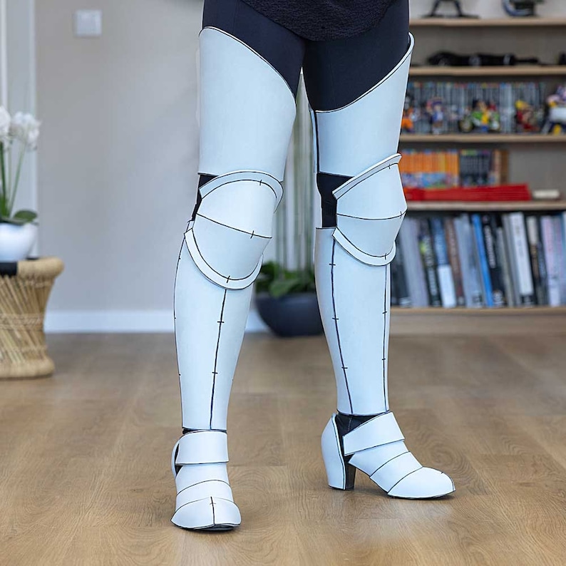 May include: White knee-high boots with a black and white pattern. The boots have a high heel and a strap around the ankle.