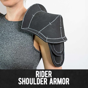 May include: Black shoulder armor with white outline detail, worn on a person's shoulder. The armor has a layered design and is labeled "RIDER SHOULDER ARMOR" in white text on a black bar at the bottom.