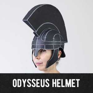 Puede incluir: Un casco negro con una cresta alta y contornos blancos, que presenta un protector nasal y placas laterales. El casco tiene un diseño estructurado y segmentado con líneas blancas visibles que trazan los paneles. Texto ODYSSEUS HELMET abajo.
