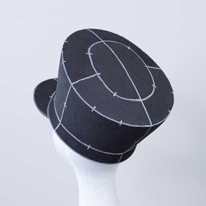 May include: A black hat with a white grid pattern on the top. The hat has a brim that is turned up on one side.