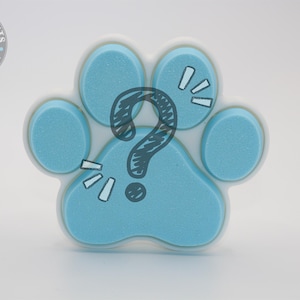 May include: A light blue paw-shaped item with a white border and a black question mark in the center. The paw has a textured appearance and is decorated with white cartoon-style accents. The Pawpular Prints logo is in the upper left corner.
