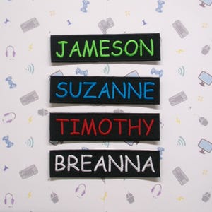 May include: Four black fabric patches with white stitching. The patches have the names "Jameson", "Suzanne", "Timothy", and "Breanna" embroidered in different colored thread.