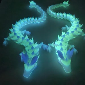 May include: Two glowing blue and green dragon figurines with spiky scales and pointed heads.