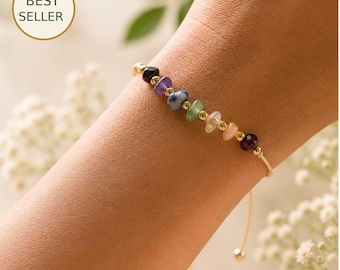 May include: A delicate bracelet featuring a series of small, polished, multi-colored gemstone chips interspersed with tiny gold-toned metal beads. The bracelet has a thin, adjustable cord and includes a circular badge with the text BEST SELLER.