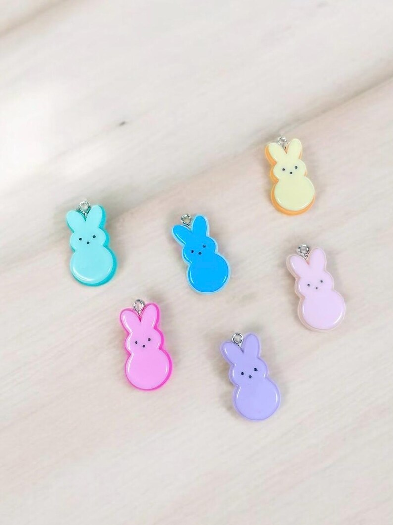 May include: Six pastel-colored bunny charms with silver jump rings. The bunnies are in shades of yellow, blue, light blue, pink, purple, and light pink.