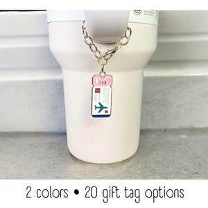May include: A gold chain with a pink and blue airplane ticket charm that says "Adventure Awaits".