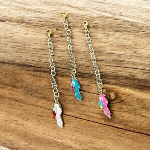 May include: Three gold chains with colorful parrot charms. The parrots are blue, white, and pink.