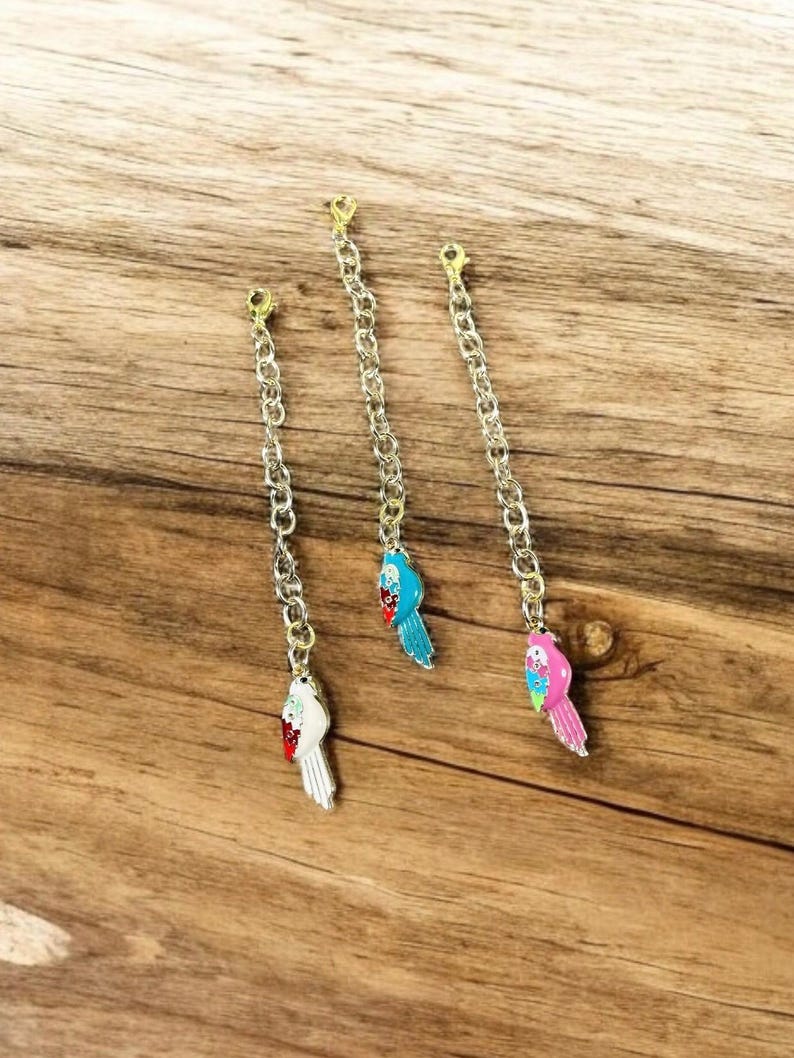 May include: Three gold chains with colorful parrot charms. The parrots are blue, white, and pink.