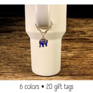 May include: A white tumbler with a gold chain and a blue elephant charm. The charm is detailed with colorful gems. The text at the bottom reads "6 colors &bull; 20 gift tags."