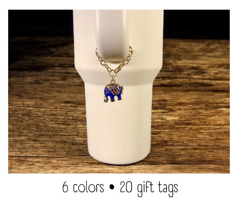 May include: A white tumbler with a gold chain and a blue elephant charm. The charm is detailed with colorful gems. The text at the bottom reads "6 colors &bull; 20 gift tags."