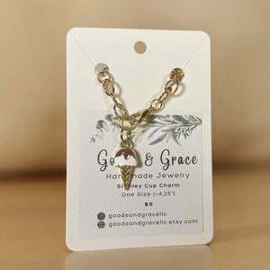May include: A gold chain bracelet with a charm of a brown and white ice cream cone. The charm is attached to a gold lobster clasp. The bracelet is on a white card with the text "Go & Grace Handmade Jewelry Stanley Cup Charm One Size (-4.25") &pound;8 goodsandgracelic goodsandgracelic.etsy.com"