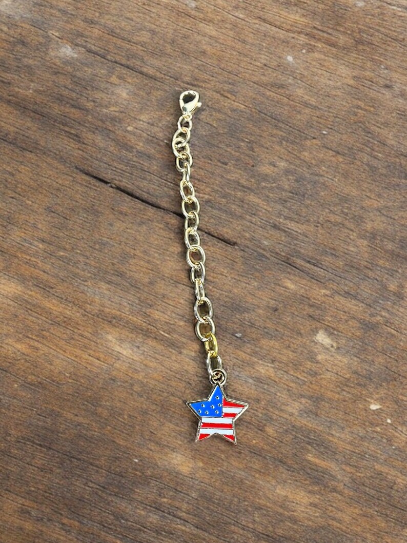 May include: A gold chain with a star-shaped charm featuring the American flag colors of red, white, and blue.