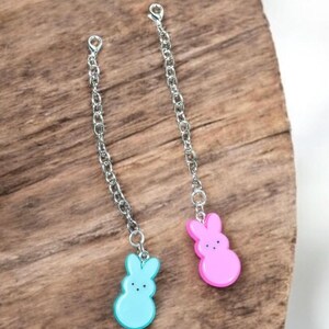 May include: Two silver chains with bunny-shaped charms. The bunny charms are made of pastel pink and blue plastic.
