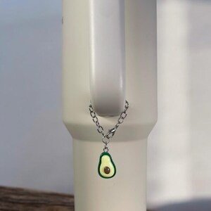 May include: A white stainless steel tumbler with a silver chain and a green avocado charm.