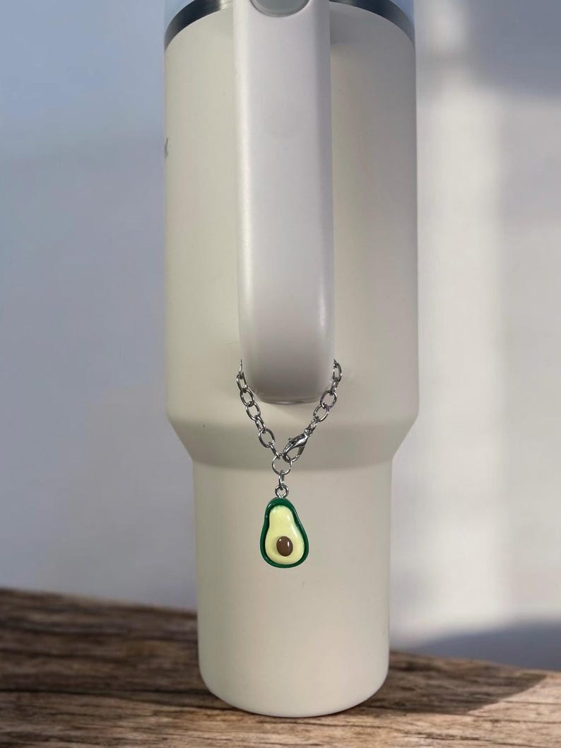 May include: A white stainless steel tumbler with a silver chain and a green avocado charm.