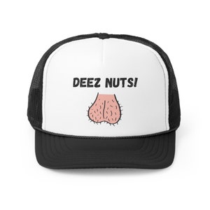 May include: A black and white trucker hat with the phrase "DEEZ NUTS!" printed in black above a cartoon illustration of a pair of testicles. The hat has a white front panel and a black brim and mesh back.