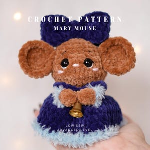 May include: A handmade crochet mouse toy, featuring a brown body, large ears, and a blue bow. The mouse wears a blue dress with a gold bell and has the text "CROCHET PATTERN MARY MOUSE" and "LOW SEW ADVANCED LEVEL".