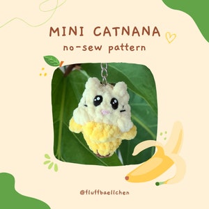 Könnte beinhalten: Ein gelber und weißer katzenförmiger Schlüsselanhänger mit einem bananenförmigen Körper. Der Schlüsselanhänger ist aus Garn gefertigt und hat ein Nähmuster. Der Text "MINI CATNANA no-sew pattern" steht über dem Schlüsselanhänger. Der Text "@fluffbaellchen" steht unter dem Schlüsselanhänger.
