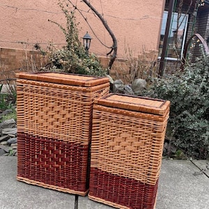 Puede incluir: Dos cestas de almacenamiento de mimbre tejido con tapas. Las cestas son de color marrón y rojo con un patrón geométrico.