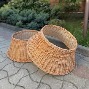 Puede incluir: Dos cestas de mimbre marrón, una ligeramente más grande que la otra, están sentadas sobre una superficie de hormigón gris. Las cestas están hechas de mimbre tejido y tienen una forma redondeada.