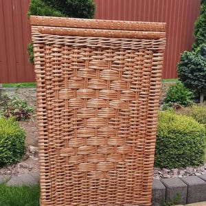 Könnte beinhalten: Ein großer, rechteckiger Korb aus Weide mit einem geflochtenen Muster. Der Korb ist aus natürlichem braunem Weidengeflecht gefertigt und hat eine glatte, gleichmäßige Textur.