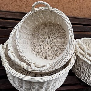 Puede incluir: Un conjunto de tres cestas blancas tejidas de diferentes tamaños, anidadas entre sí. Cada cesta tiene forma redonda y un asa tejida. Las cestas están hechas de un material de color claro y son adecuadas para almacenamiento o decoración.