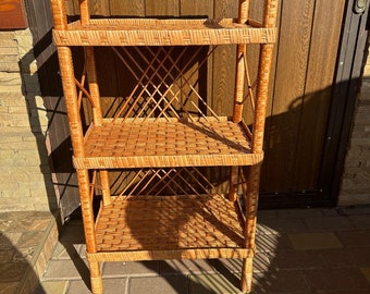 May include: A three-tiered wicker shelf unit with a natural brown finish. The shelf is made of woven wicker and has a simple, rustic design.