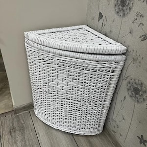 May include: White wicker corner laundry basket with a lid. The basket is woven with a diamond pattern.