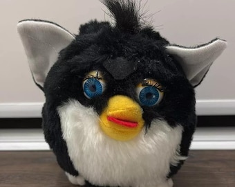 May include: Black and white plush toy with blue eyes and a yellow beak. The toy has a white fur belly and a black fur body.