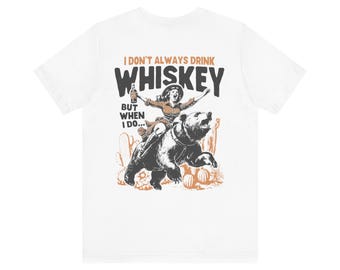 May include: White t-shirt with a graphic print of a woman riding a bear. The text on the shirt reads "I don't always drink whiskey, but when I do..."