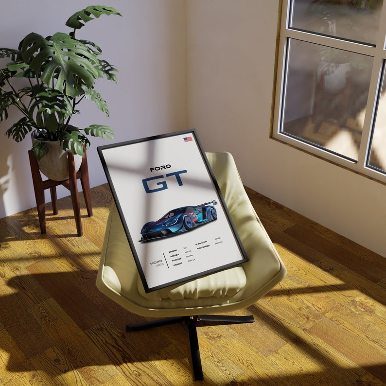 May include: A framed poster with a blue and white Ford GT race car on a white background. The poster has the text "FORD GT" in black and white. The poster is sitting on a light brown armchair.