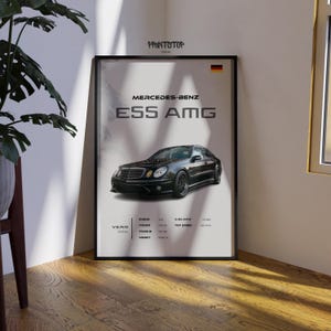 May include: Framed poster featuring a black Mercedes-Benz E55 AMG. The poster includes the text "Mercedes-Benz E55 AMG" and the year 2006. The German flag is in the upper right corner. The poster is in a black frame.