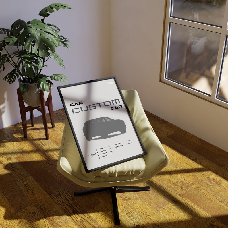 May include: A black framed poster with the text "CAR CUSTOM CAR" and a silhouette of a car. The poster is sitting on a light beige armchair with a black base.