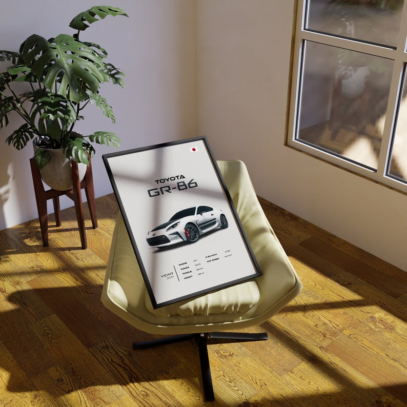May include: A black framed poster with a white Toyota GR-86 sports car on a white background. The poster has the text "TOYOTA GR-86" in black and white text. The poster also has the text "YEAR 2021" in black text.