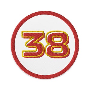 May include: A red and white circular patch with a yellow outline. The number 38 is embroidered in red with a yellow outline.