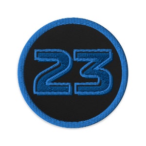 May include: A blue and black embroidered patch with the number 23 in a circle.