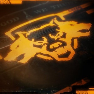 Op de afbeelding: Een gestileerde afbeelding van drie wolfskopjes in oranje tegen een donkere achtergrond. De wolfskopjes zijn naar voren gericht met hun bek open en zichtbare tanden. De afbeelding is overlegd met een wazige afbeelding van een dollarbiljet met de tekst "In God We Trust" zichtbaar.