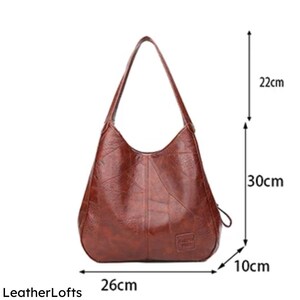 May include: A brown leather shoulder bag with a 26 cm base, 30 cm height, and 10 cm width. The bag has a curved design with a single shoulder strap, and a small logo. The strap is 22 cm long.