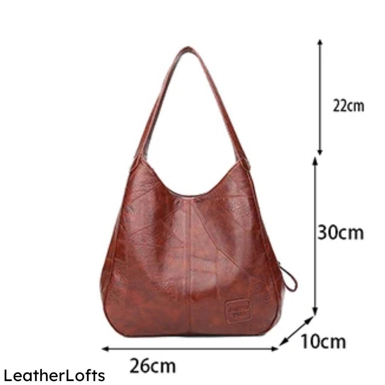 May include: A brown leather shoulder bag with a 26 cm base, 30 cm height, and 10 cm width. The bag has a curved design with a single shoulder strap, and a small logo. The strap is 22 cm long.