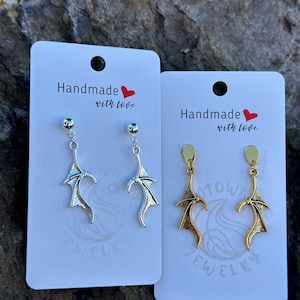May include: Two pairs of handmade earrings on white cards. One pair is silver-toned with a bat wing design, and the other is gold-toned. The cards read "Handmade with love" and "TOWN JEWELRY".