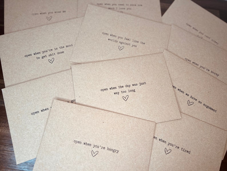 May include: A set of brown paper envelopes with handwritten messages on them. Each envelope has a different message, such as "open when you're in the mood to get stuff done" or "open when you feel like the world's against you".