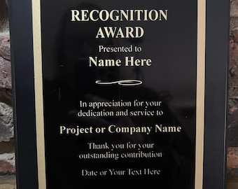 May include: A rectangular black recognition award plaque with a gold border. The text reads: RECOGNITION AWARD, Presented to Name Here, In appreciation for your dedication and service to Project or Company Name, Thank you for your outstanding contribution, Date or Your Text Here.