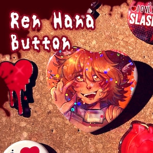 May include: Heart-shaped button with an anime-style illustration of a character with orange hair and a mischievous expression. The button has glitter accents and the text "Ren Hana Button" in a stylized font. Other heart-shaped pins are also visible.