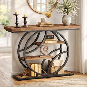 May include: A modern console table with a dark wood top and shelves, supported by a black metal circular frame. The table is decorated with candles, books, and decorative objects, creating a stylish display.