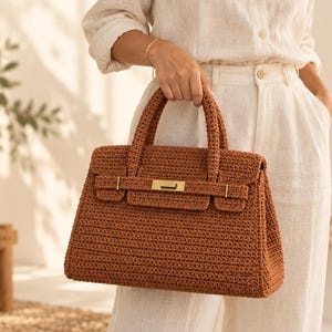 May include: A structured brown crochet handbag featuring a rectangular silhouette, two top handles, and a gold-tone metal clasp closure on the front flap. The text CROCHET PATTERN is visible in the upper left corner of the image.